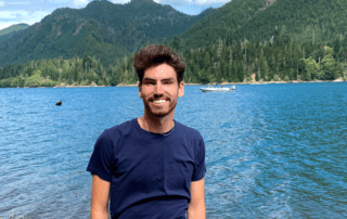 Jamison Siebart standing in front of lake with mountains in background
