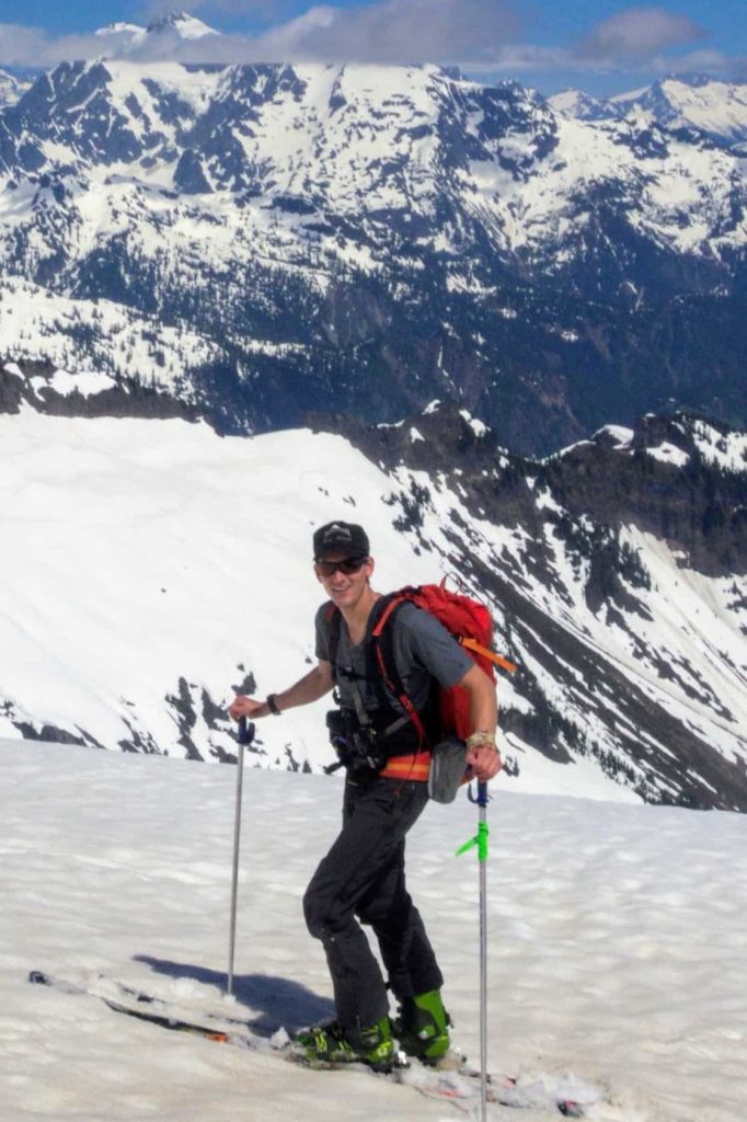 UW master's student Dylan Guelig on skis on mountaintop