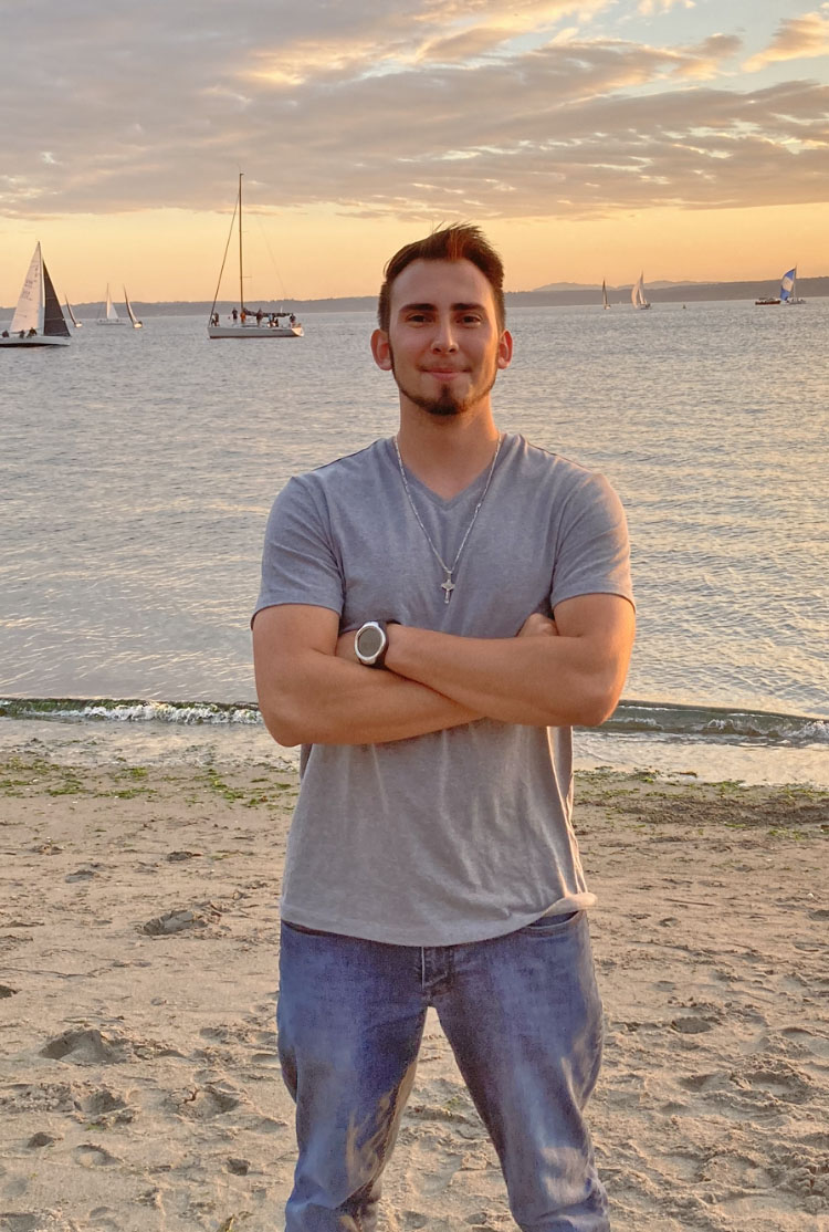 Osvaldo Arias in front of lake with sailboats, wide shot