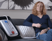 Woman sitting on sofa with portable kidney dialysis prototype next to her